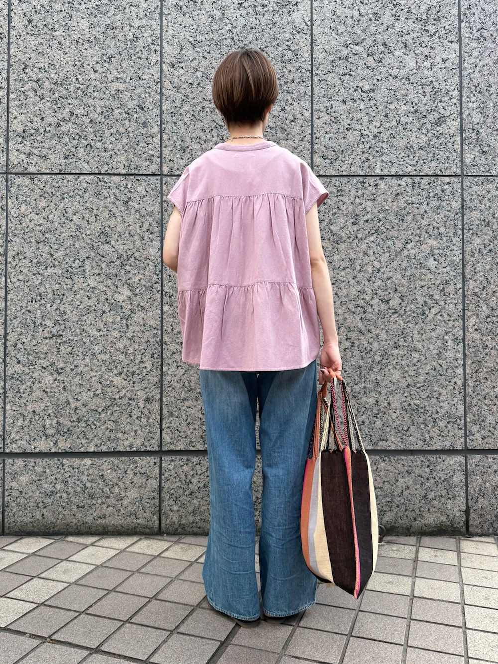 ピンク系のシャツ/ブラウス、ブルー系のデニムパンツ、ピンク系のかごバッグを着用したレディースの春コーディネートの3枚目の写真