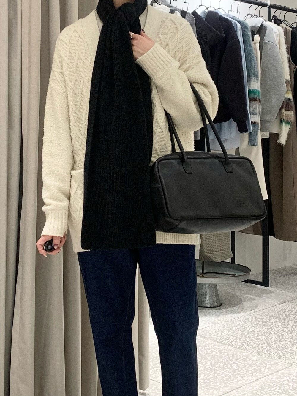 ブラック系のボストンバッグ、ブルー系のデニムパンツ、ベージュ系のスウェットを着用したレディースの冬コーディネートの4枚目の写真