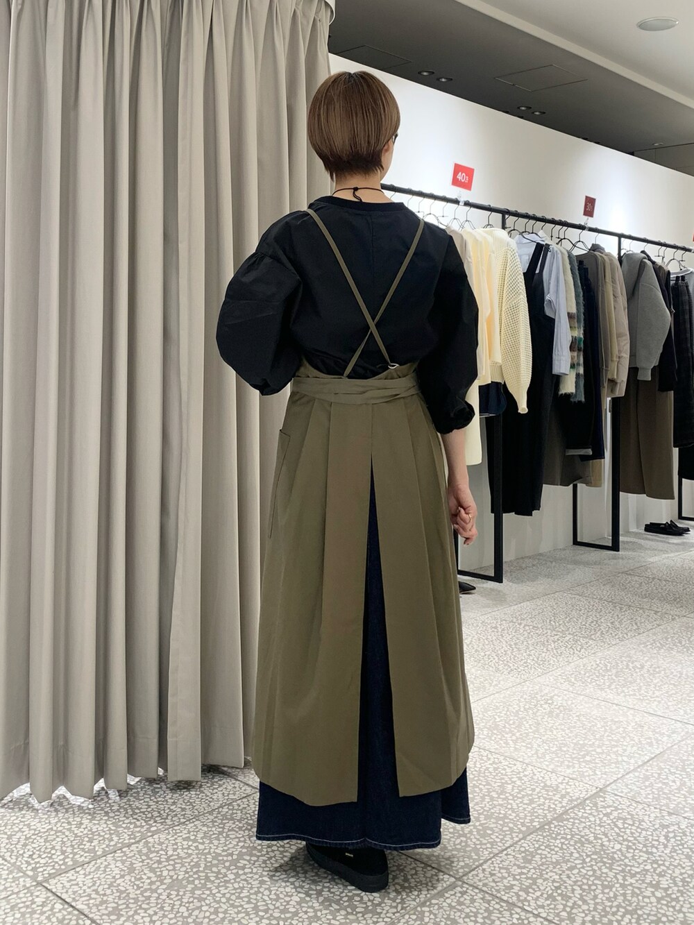 ブラック系のシャツ/ブラウス、ゴールド系のネックレス、グリーン系のエプロンを着用したレディースの冬コーディネートの3枚目の写真