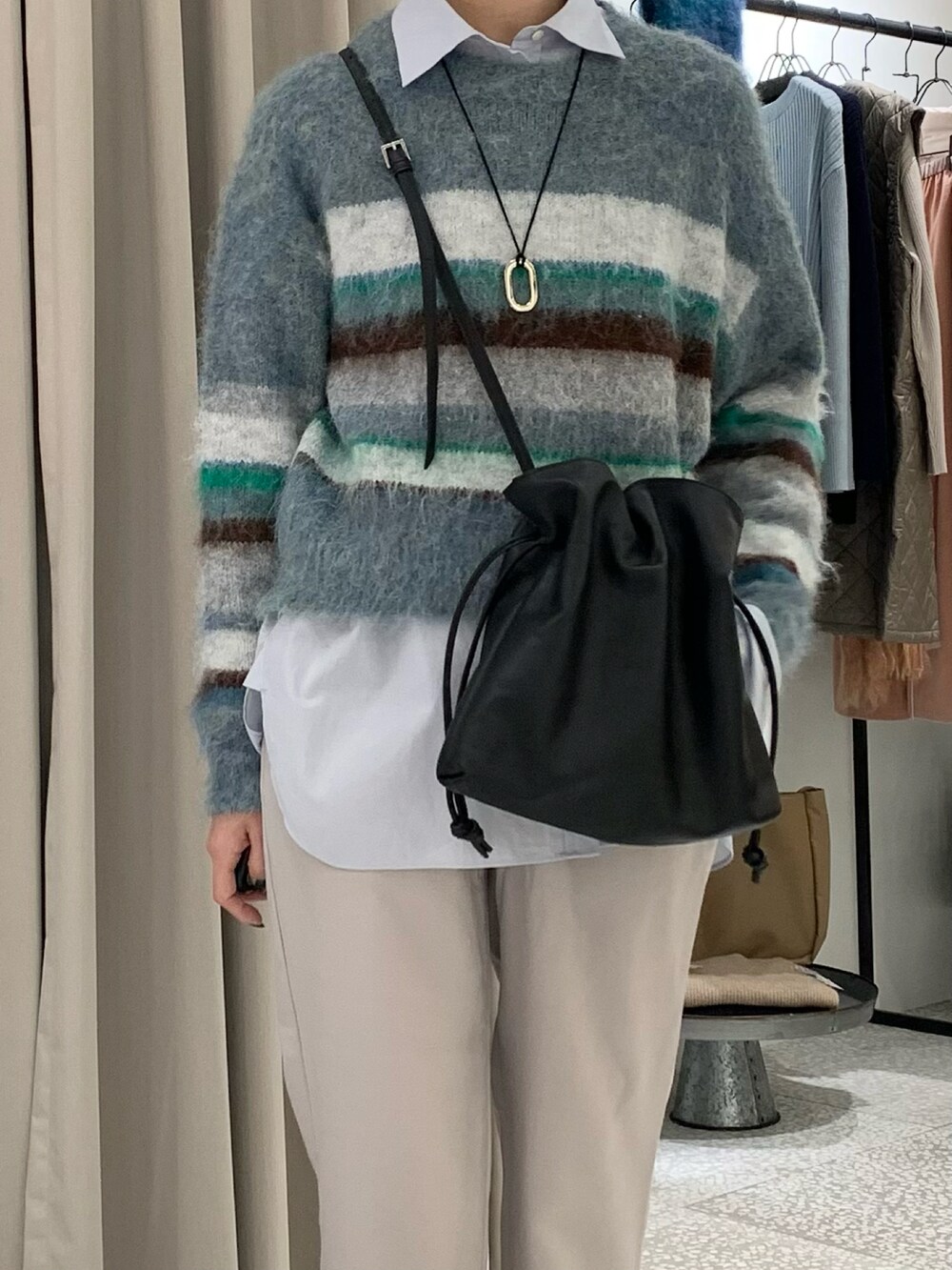 ブルー系のニット/セーター、ブラック系のショルダーバッグ、ブルー系のシャツ/ブラウスを着用したレディースの冬コーディネートの3枚目の写真