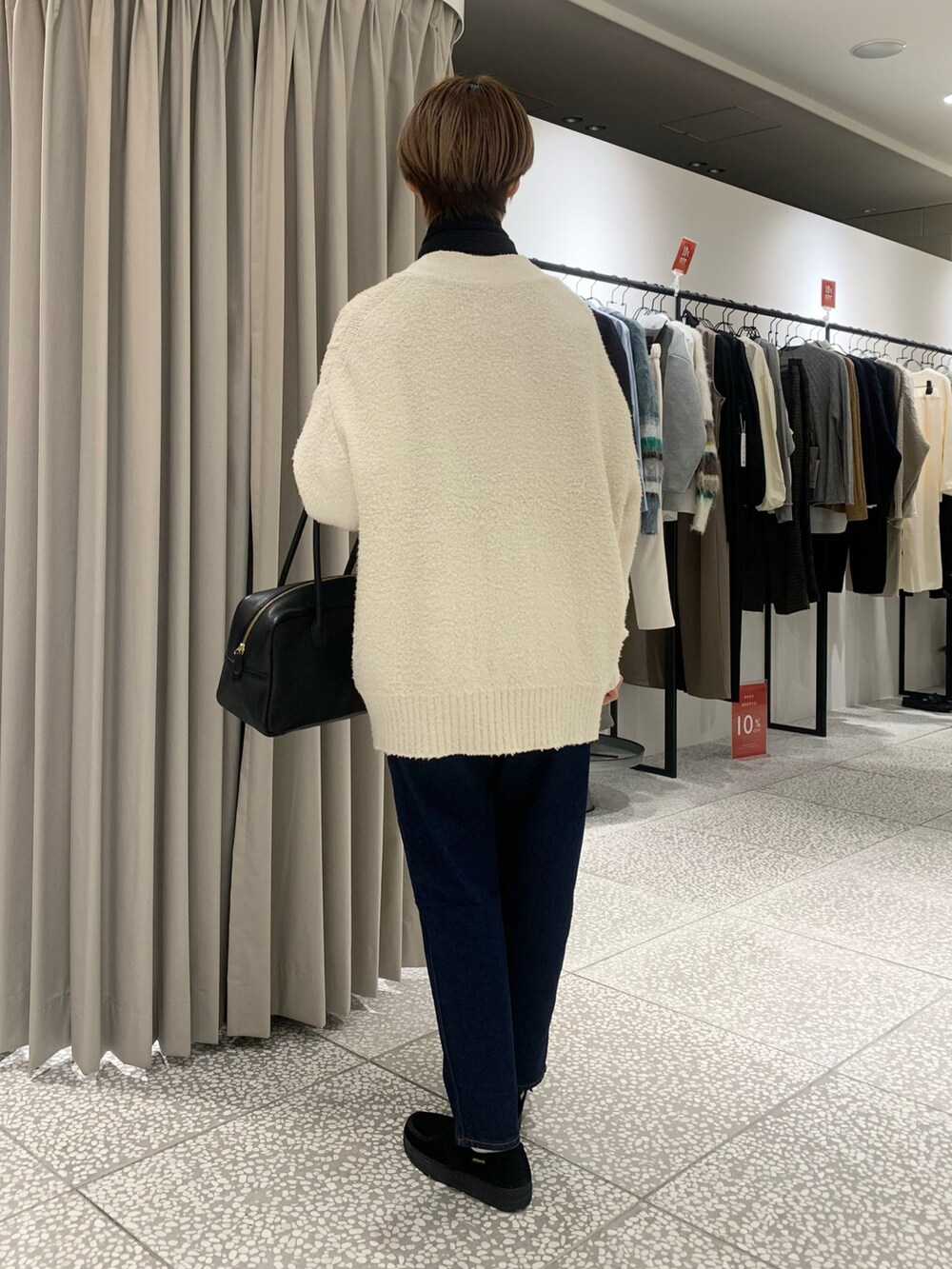 ブラック系のボストンバッグ、ブルー系のデニムパンツ、ベージュ系のスウェットを着用したレディースの冬コーディネートの3枚目の写真