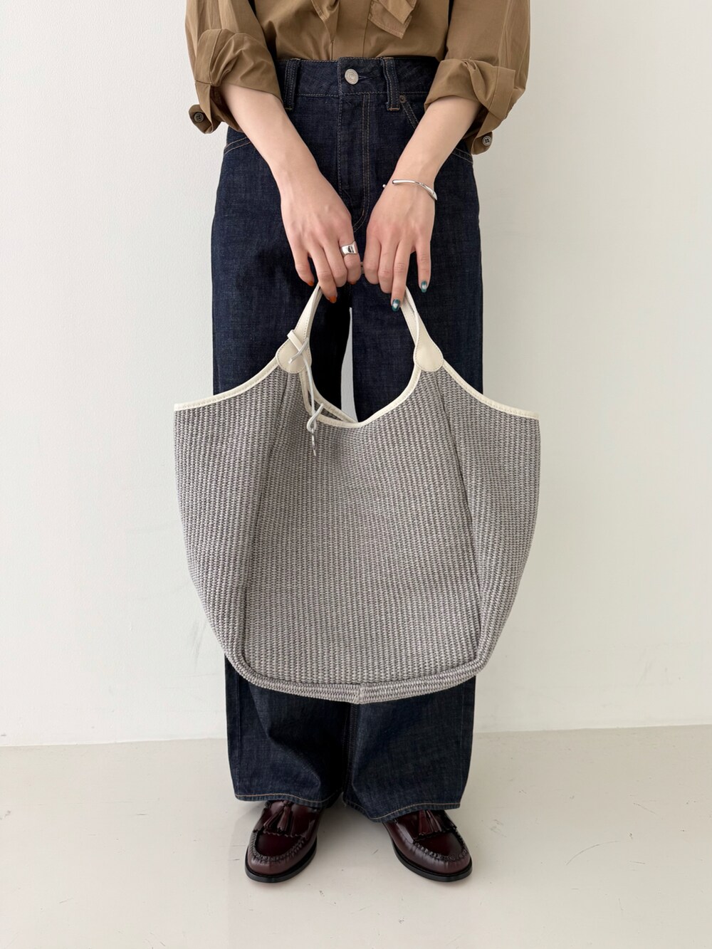 ブラウン系のシャツ/ブラウス、ブルー系のデニムパンツ、グレー系のかごバッグを着用したレディースの春コーディネートの3枚目の写真