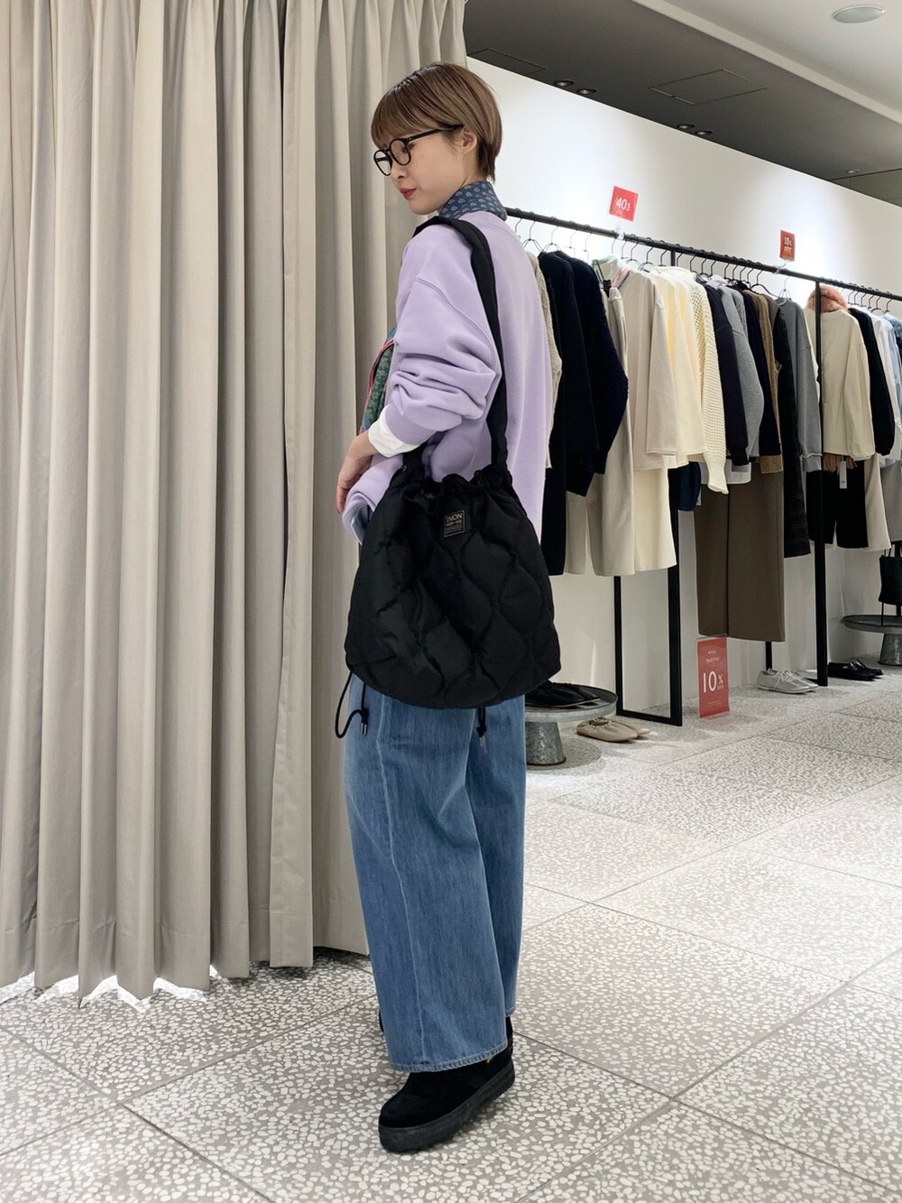 パープル系のスウェット、ブラック系のショルダーバッグ、ブルー系のデニムパンツを着用したレディースの冬コーディネートの2枚目の写真