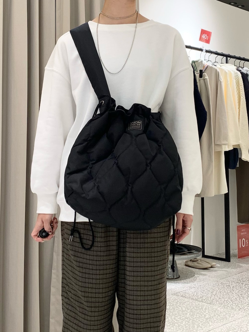 ホワイト系のスウェット、ブラック系のショルダーバッグ、ブラウン系のその他パンツを着用したレディースの冬コーディネートの5枚目の写真