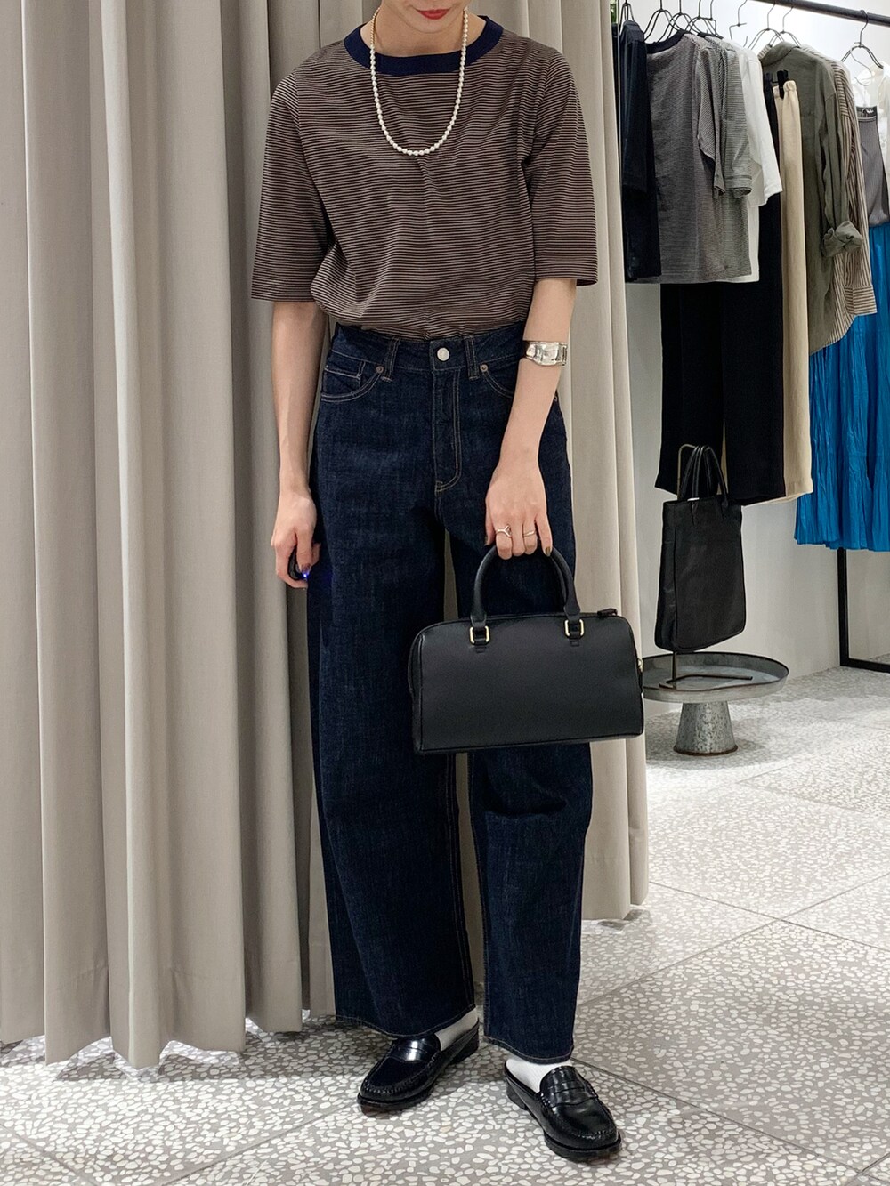 ベージュ系のTシャツ/カットソー、ブルー系のデニムパンツ、ブラック系のボストンバッグを着用したレディースの夏コーディネートの3枚目の写真