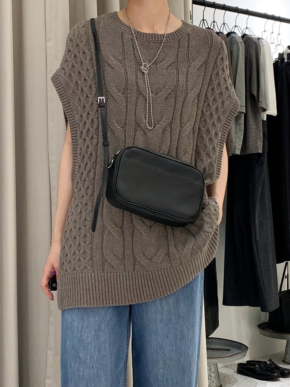 ブラック系のショルダーバッグ、ブルー系のデニムパンツ、ベージュ系のニット/セーターを着用したレディースの夏コーディネートの2枚目の写真