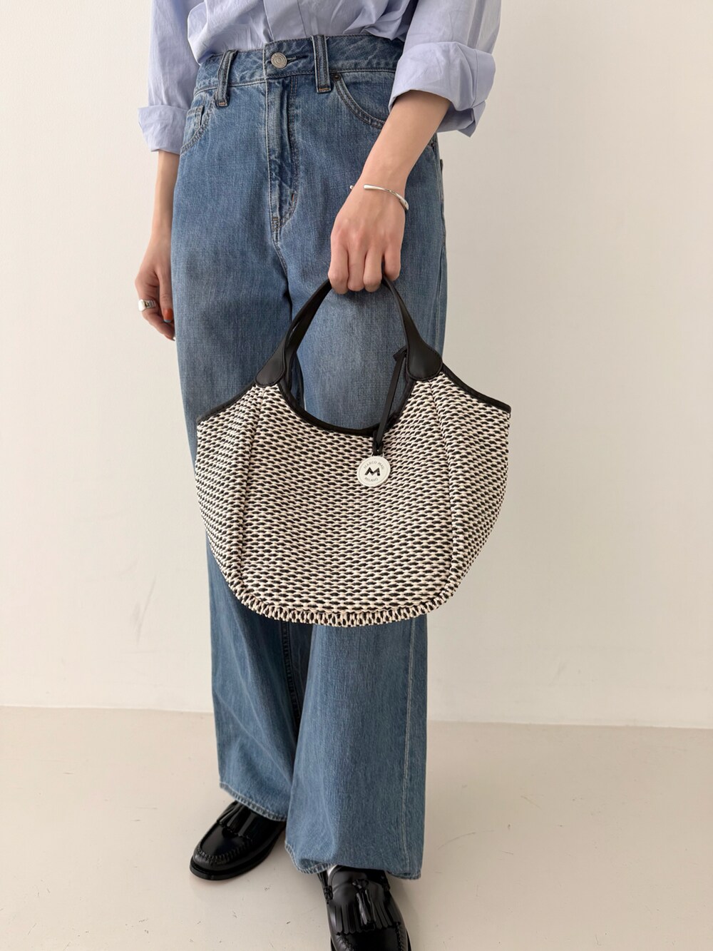 ブルー系のシャツ/ブラウス、ブルー系のデニムパンツ、ブラック系のかごバッグを着用したレディースの春コーディネートの4枚目の写真