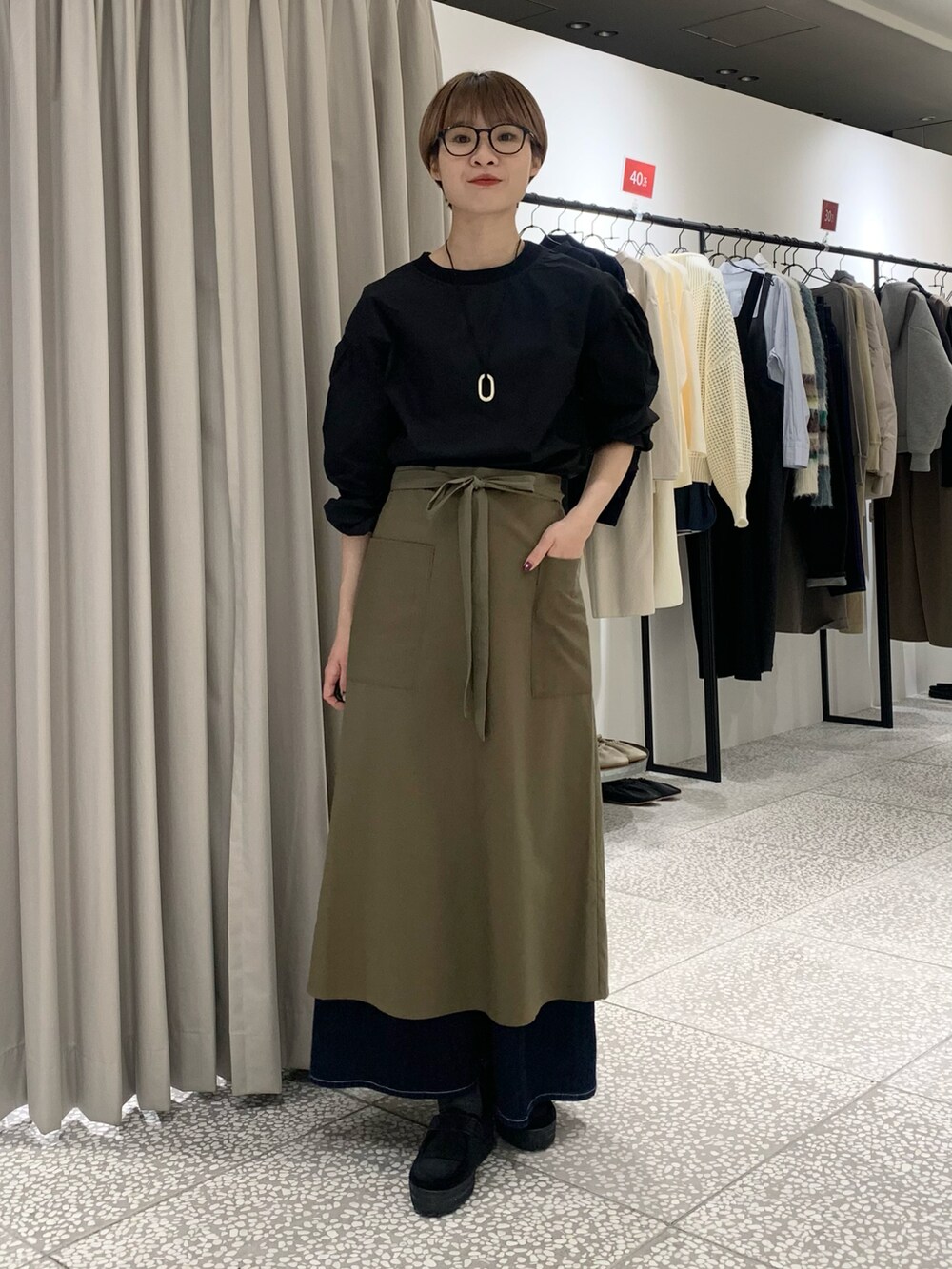 ブラック系のシャツ/ブラウス、ゴールド系のネックレス、グリーン系のエプロンを着用したレディースの冬コーディネートの4枚目の写真