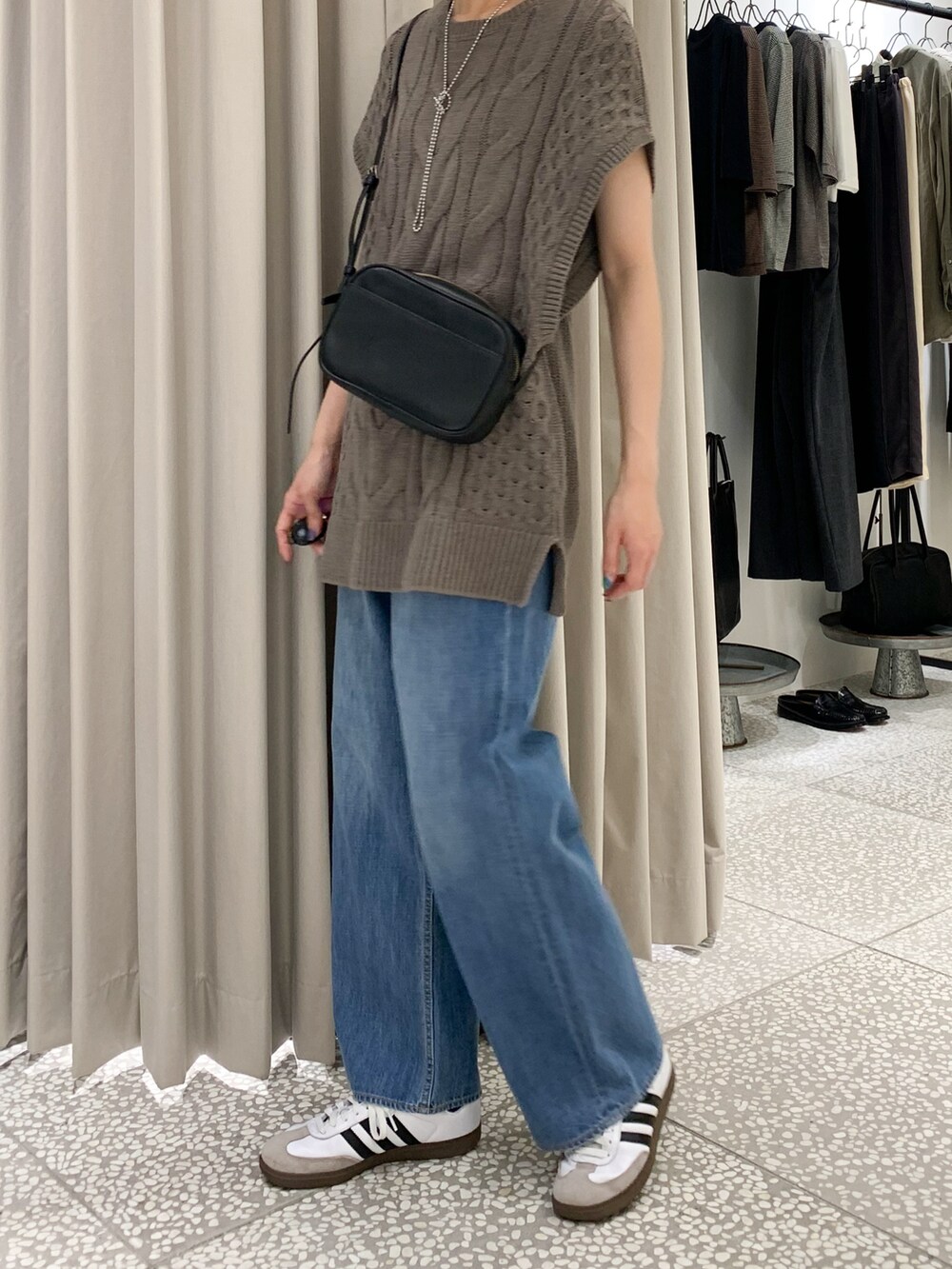 ブラック系のショルダーバッグ、ブルー系のデニムパンツ、ベージュ系のニット/セーターを着用したレディースの夏コーディネートの4枚目の写真