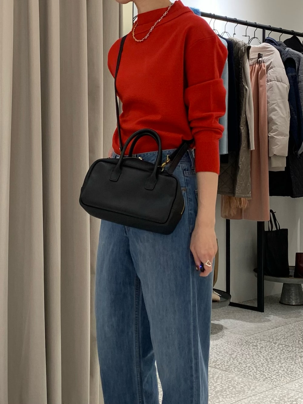 レッド系のニット/セーター、ブラック系のショルダーバッグ、ブルー系のデニムパンツを着用したレディースの冬コーディネートの4枚目の写真