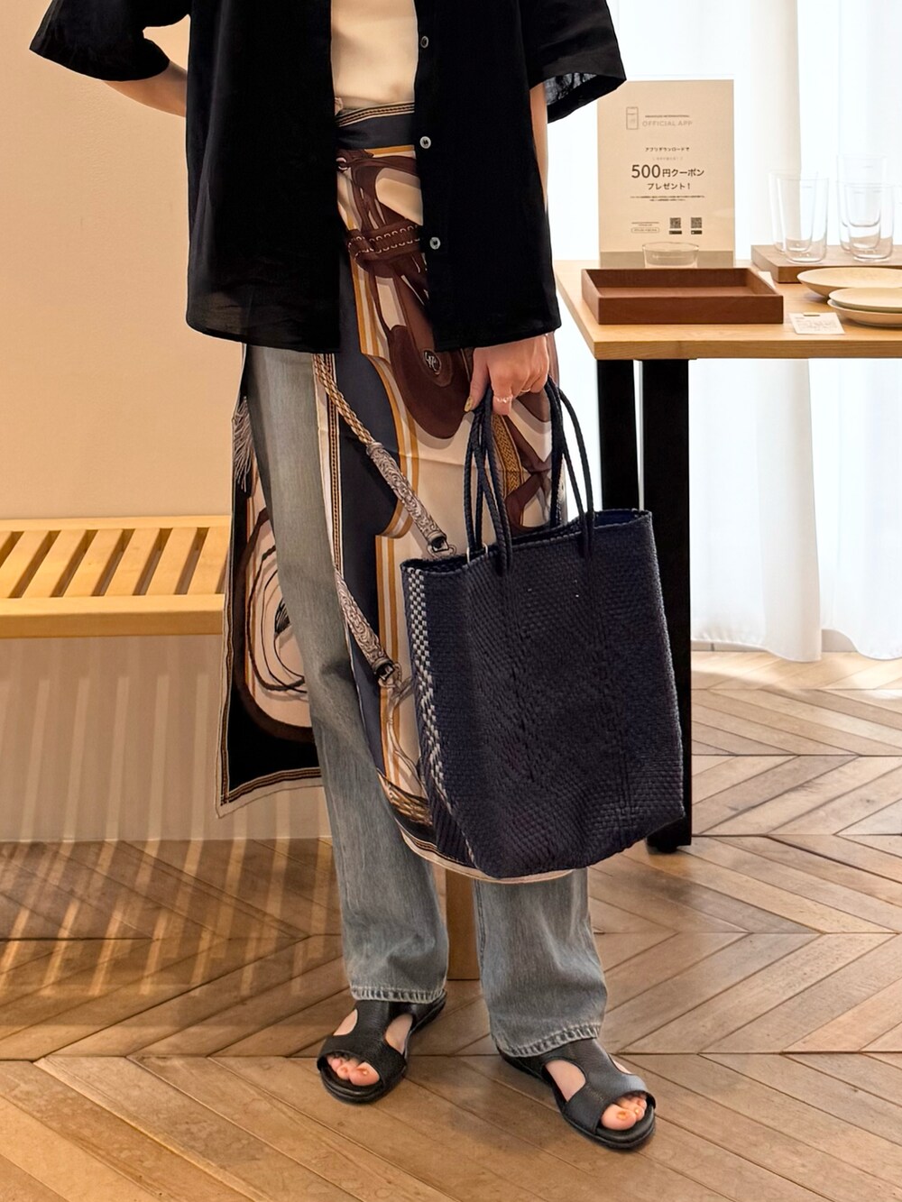 ブラック系のシャツ/ブラウス、ブラック系のサンダル、ブルー系のかごバッグを着用したレディースの夏コーディネートの2枚目の写真