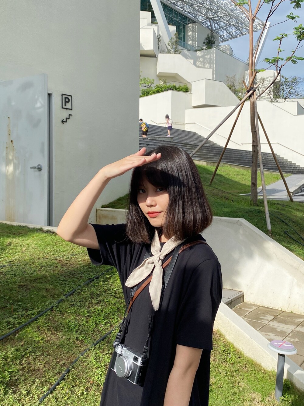 ブラック系のチュニック、ブラック系のブーティ、ベージュ系のストール/ショールを着用したレディースの夏コーディネートの3枚目の写真