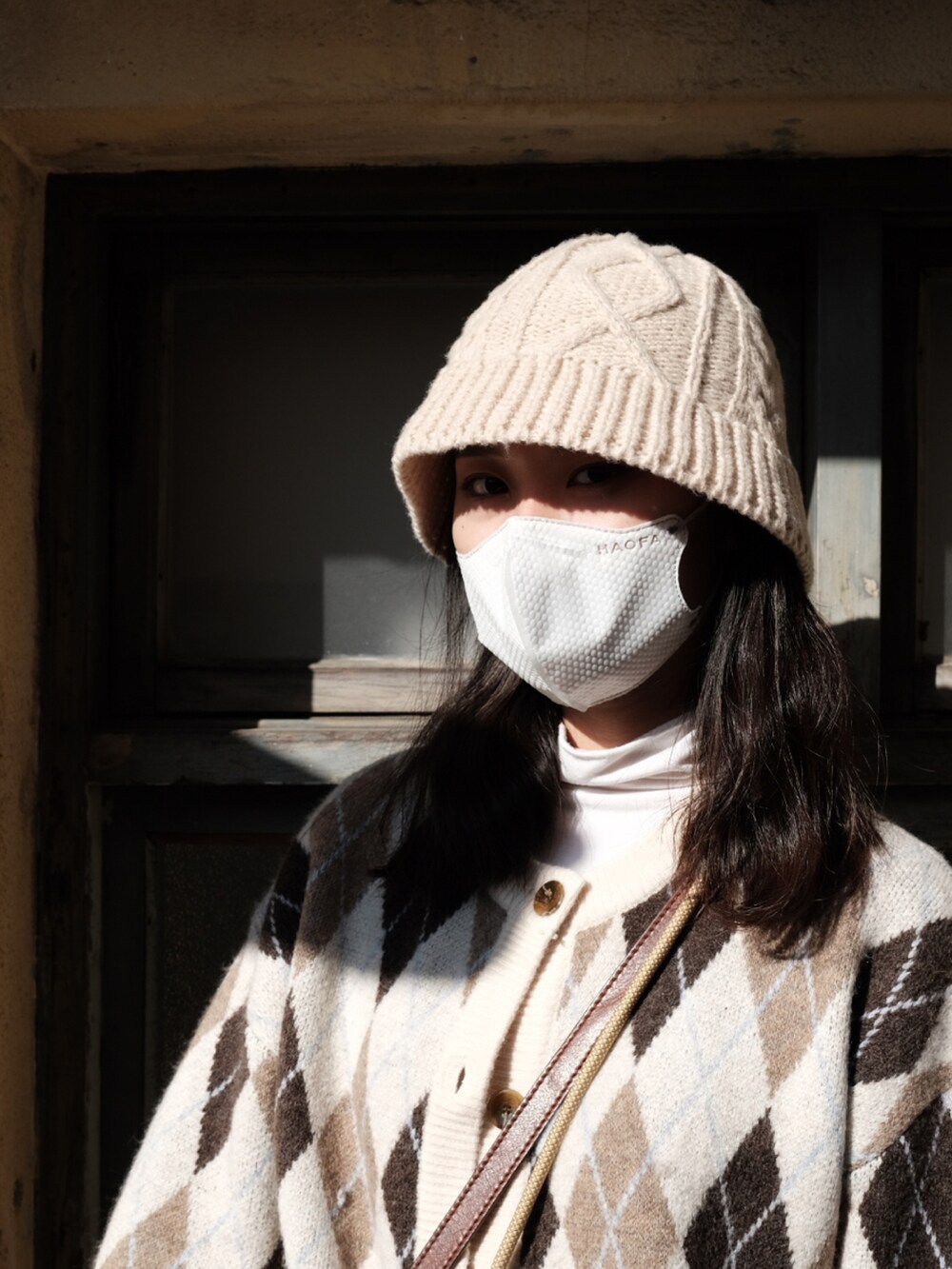 ベージュ系のダッフルコート、ブラック系のスカート、ブラック系のブーツを着用したレディースの冬コーディネートの2枚目の写真