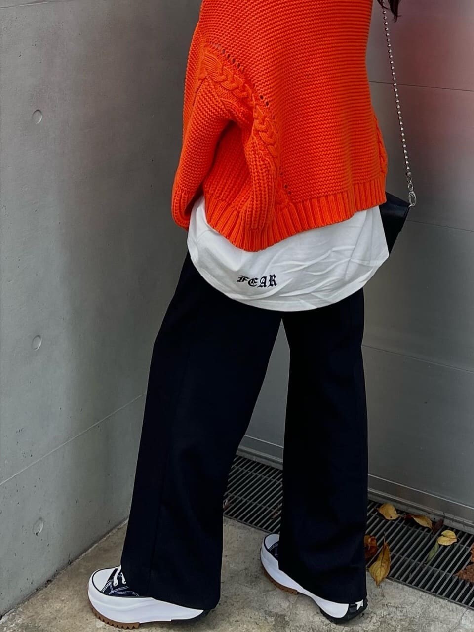 オレンジ系のニット/セーター、ブラック系のスラックスを着用したレディースの秋コーディネートの5枚目の写真