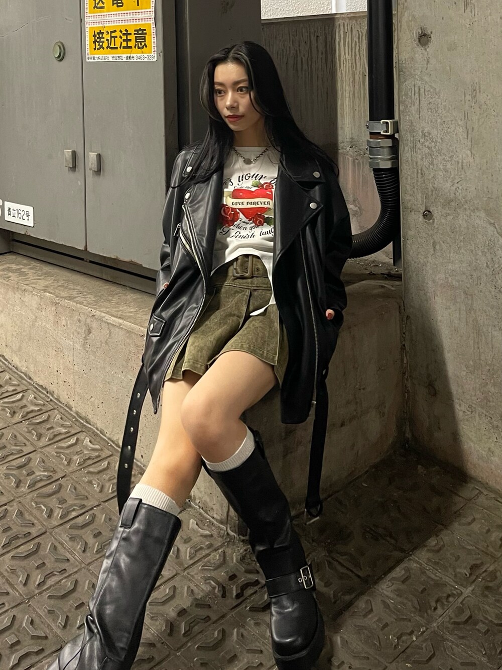 ブラック系のライダースジャケット、レッド系のTシャツ/カットソー、ベージュ系のスカートを着用したレディースの冬コーディネートの3枚目の写真
