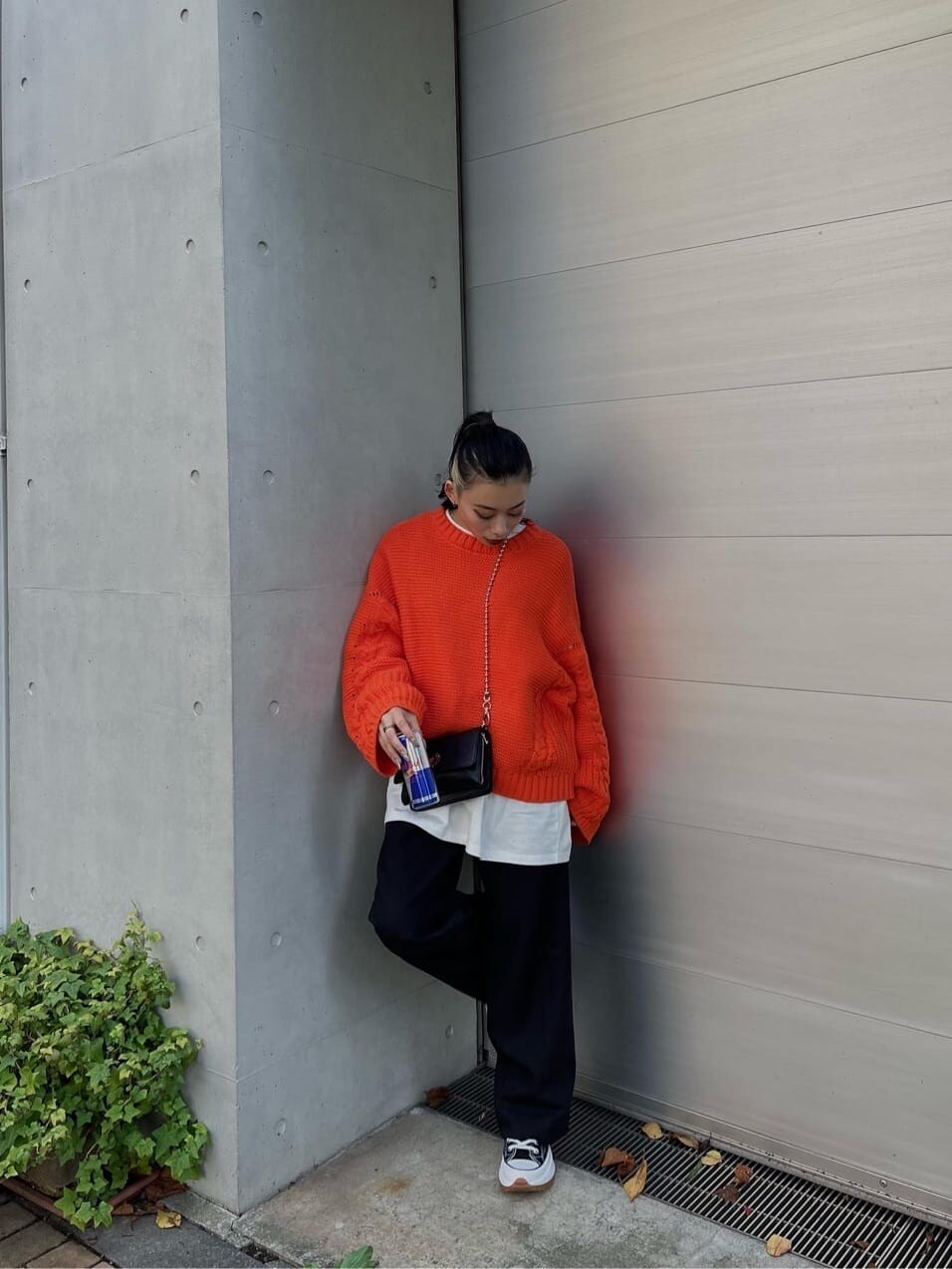 オレンジ系のニット/セーター、ブラック系のスラックスを着用したレディースの秋コーディネートの3枚目の写真