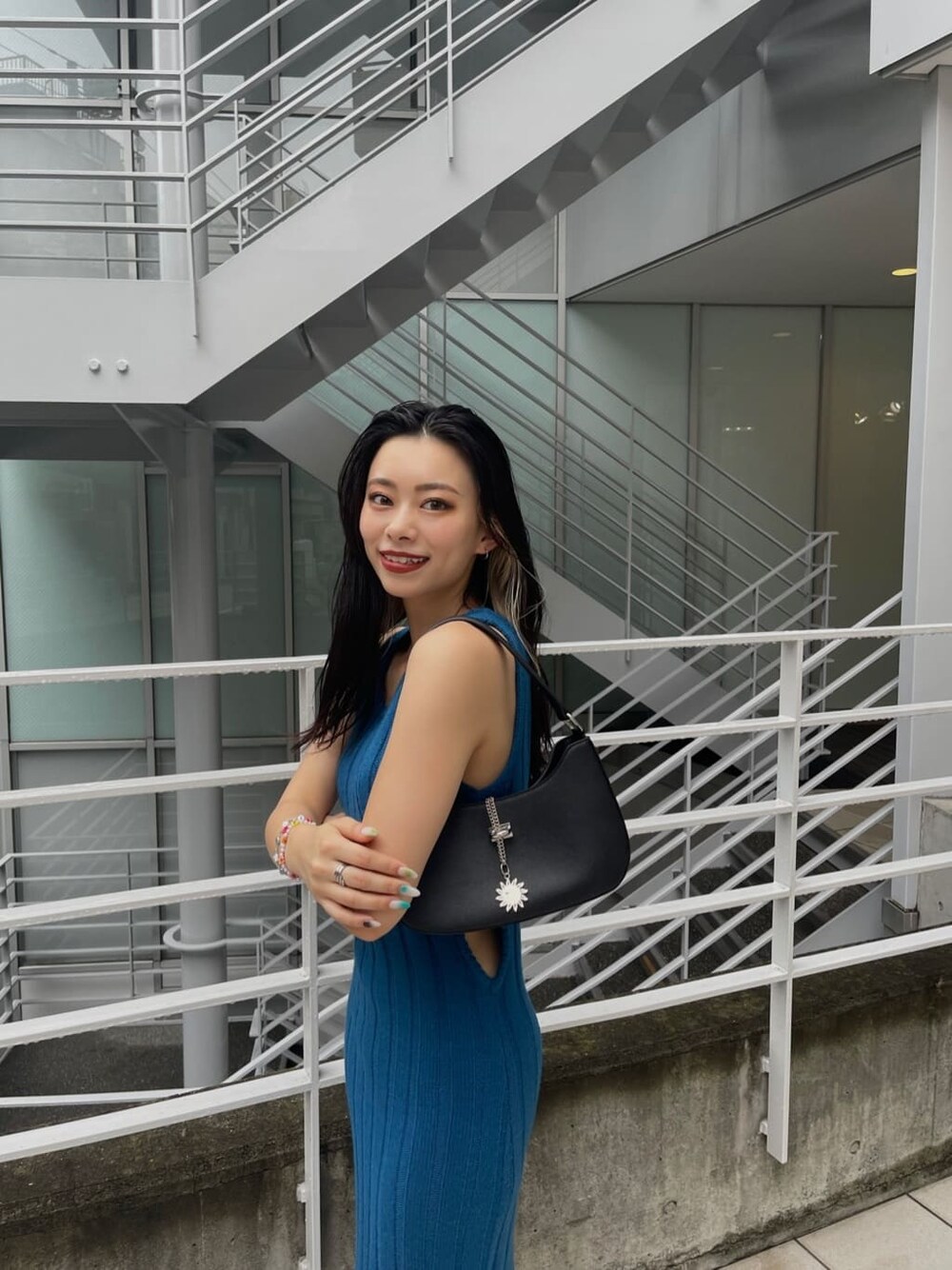 ブルー系のワンピース、ブラック系のハンドバッグ、ブラック系のブーツを着用したレディースの秋コーディネートの4枚目の写真