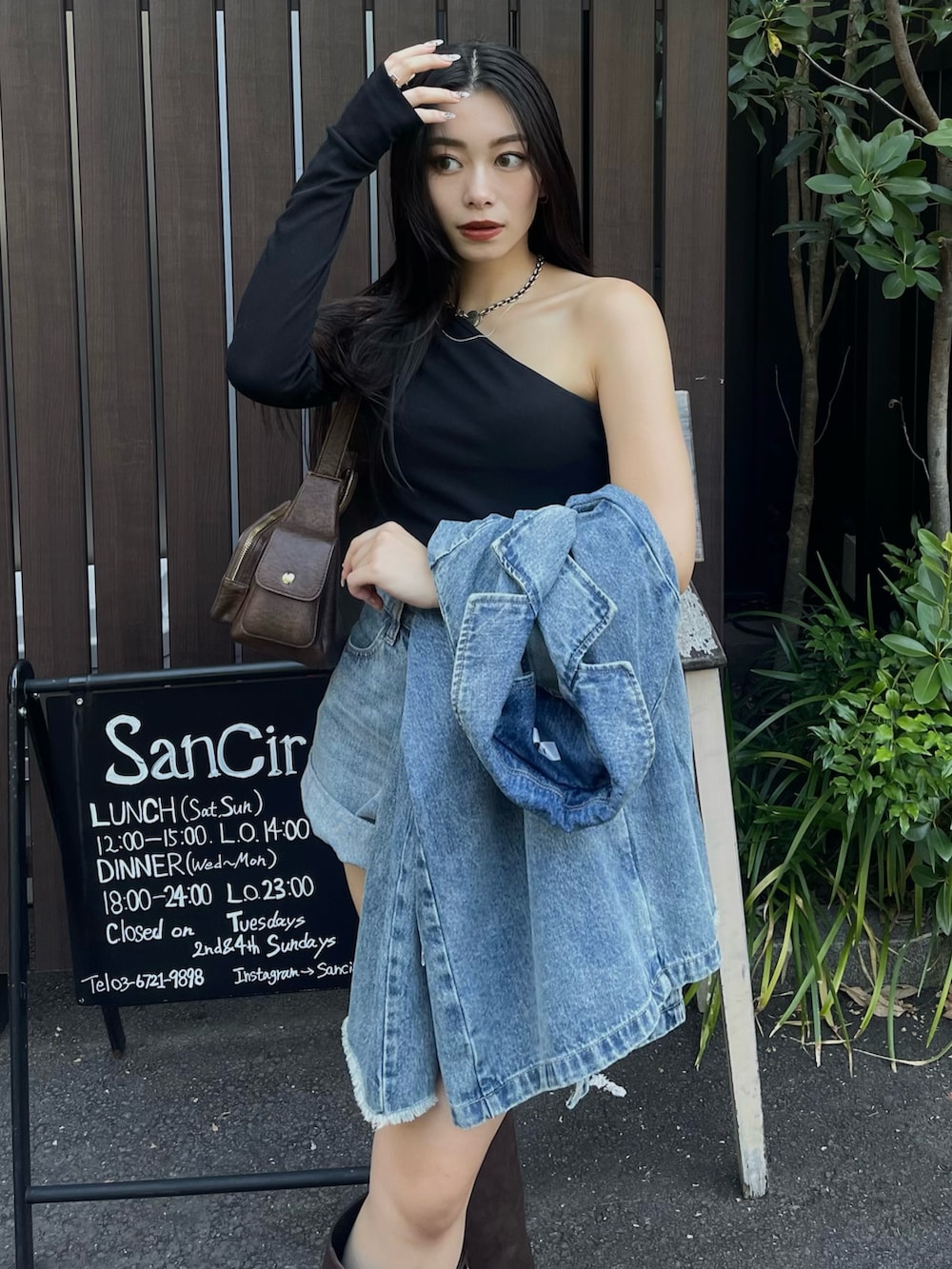 ブルー系のデニムジャケット、ブラック系のTシャツ/カットソー、ブラウン系のブーツを着用したレディースの夏コーディネートの3枚目の写真