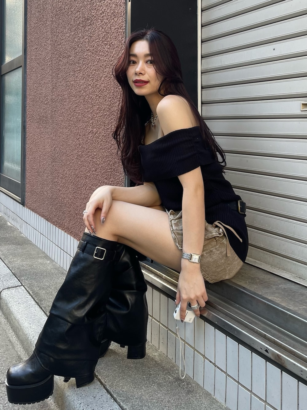 ブラック系のニット/セーター、ベージュ系のスカート、ブラック系のブーツを着用したレディースの春コーディネートの3枚目の写真