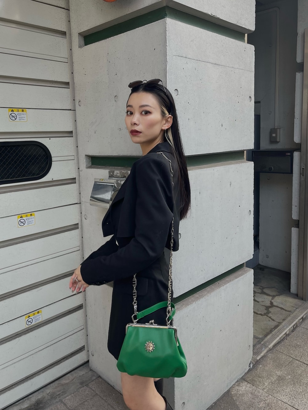 ブラック系のテーラードジャケット、ブラック系のスカート、グリーン系のショルダーバッグを着用したレディースの冬コーディネートの2枚目の写真