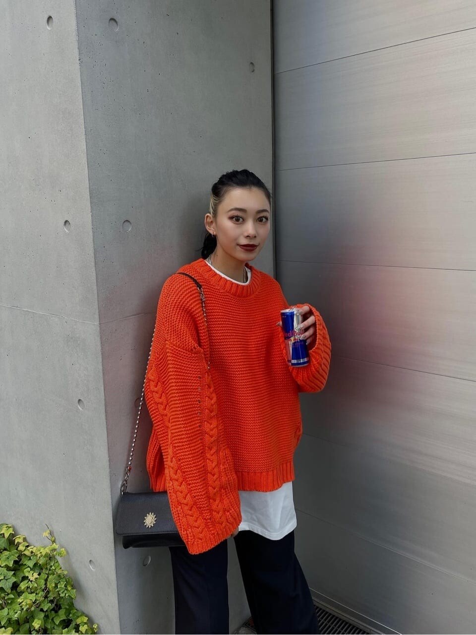 オレンジ系のニット/セーター、ブラック系のスラックスを着用したレディースの秋コーディネートの2枚目の写真