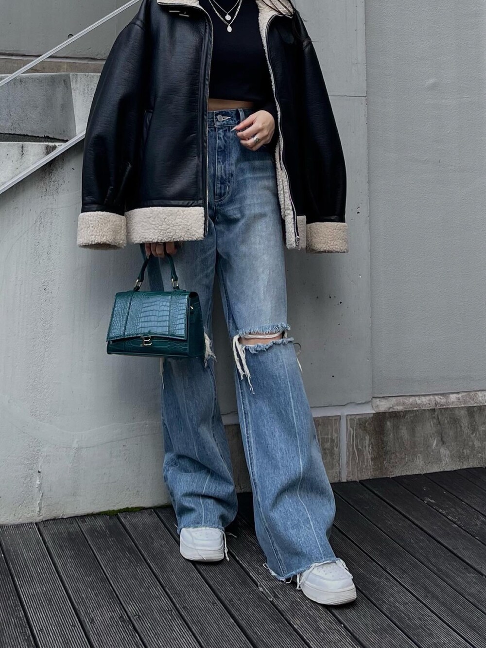 ブラック系のブルゾン、ブラック系のニット/セーター、ブルー系のデニムパンツを着用したレディースの秋コーディネートの4枚目の写真