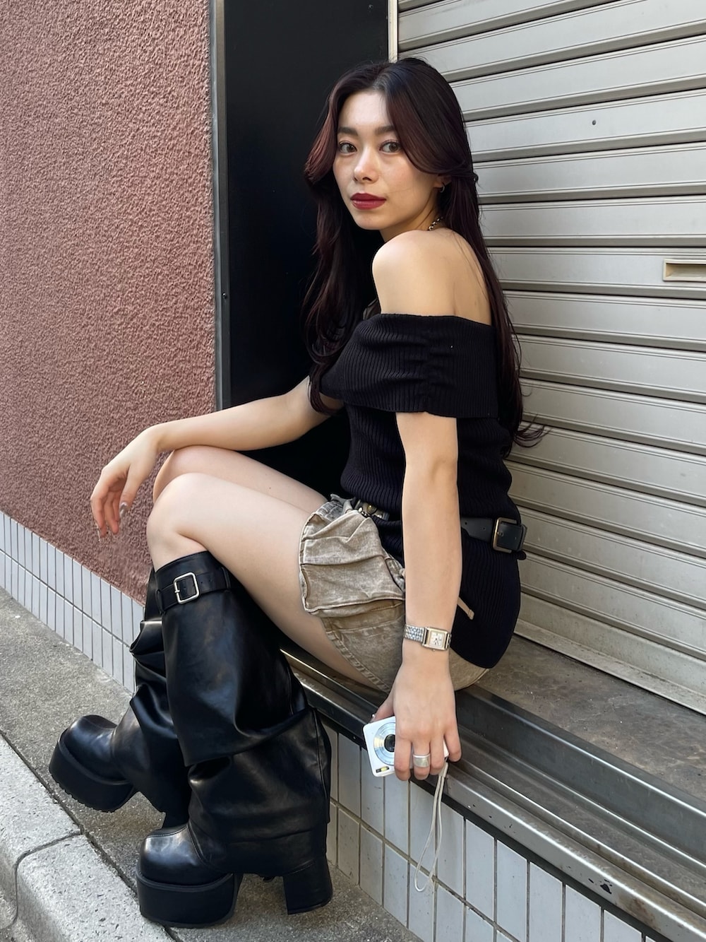 ブラック系のニット/セーター、ベージュ系のスカート、ブラック系のブーツを着用したレディースの春コーディネートの2枚目の写真