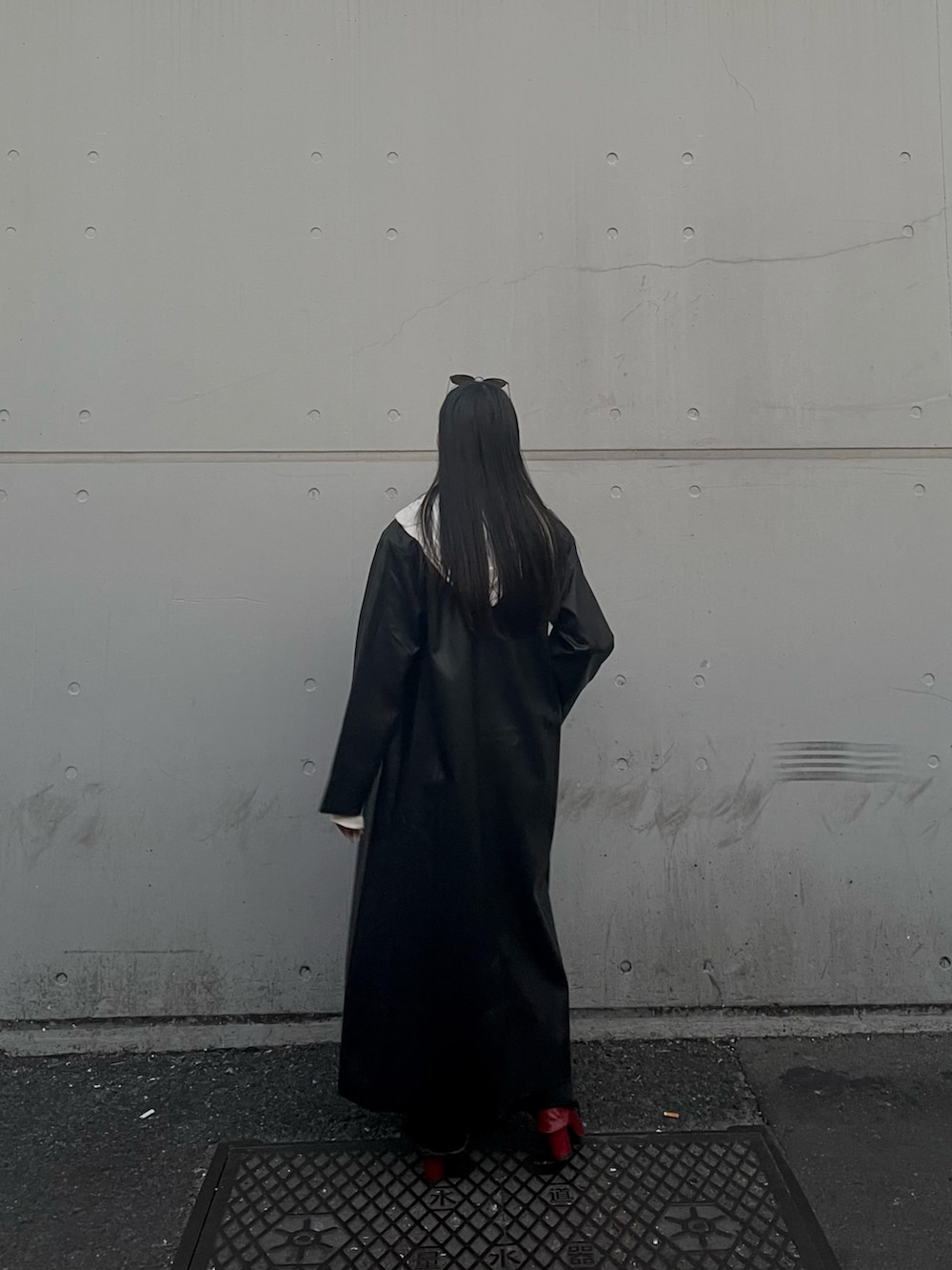 ブラック系のチェスターコート、レッド系のブーツ、ブラック系のデニムパンツを着用したレディースの冬コーディネートの3枚目の写真