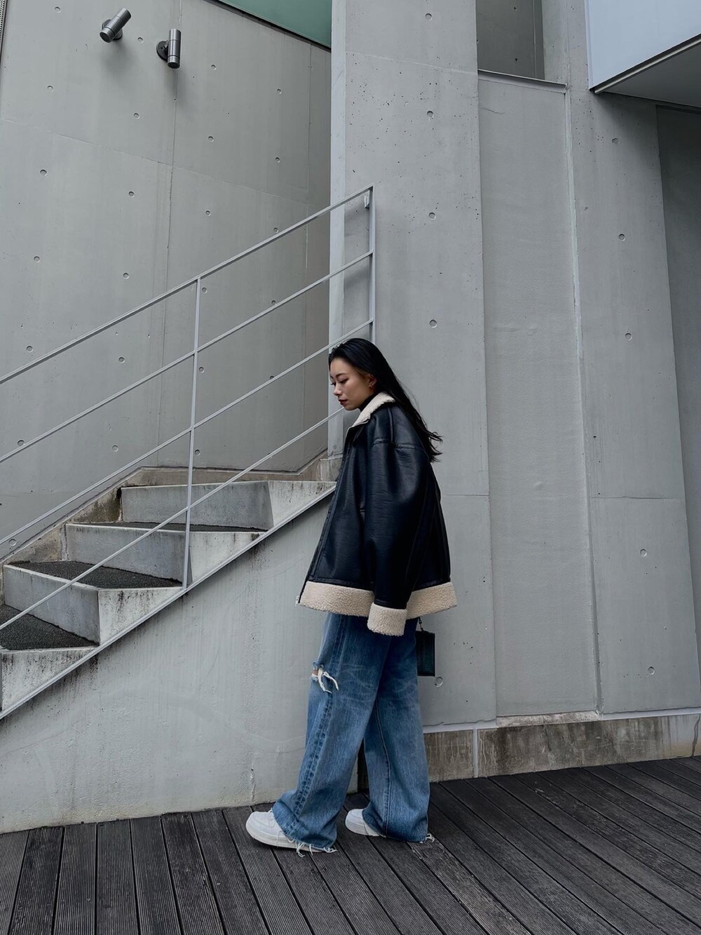 ブラック系のブルゾン、ブラック系のニット/セーター、ブルー系のデニムパンツを着用したレディースの秋コーディネートの3枚目の写真