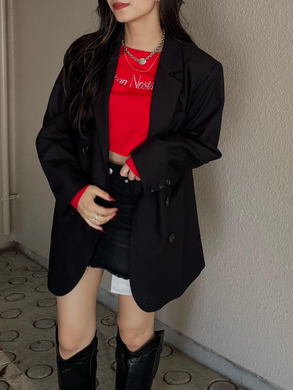 レッド系のTシャツ/カットソー、ブラック系のデニムスカート、ブラック系のブーツを着用したレディースの秋コーディネートの4枚目の写真