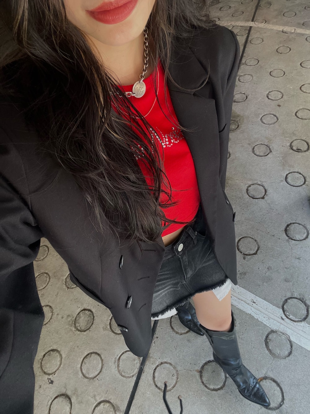 レッド系のTシャツ/カットソー、ブラック系のデニムスカート、ブラック系のブーツを着用したレディースの秋コーディネートの5枚目の写真