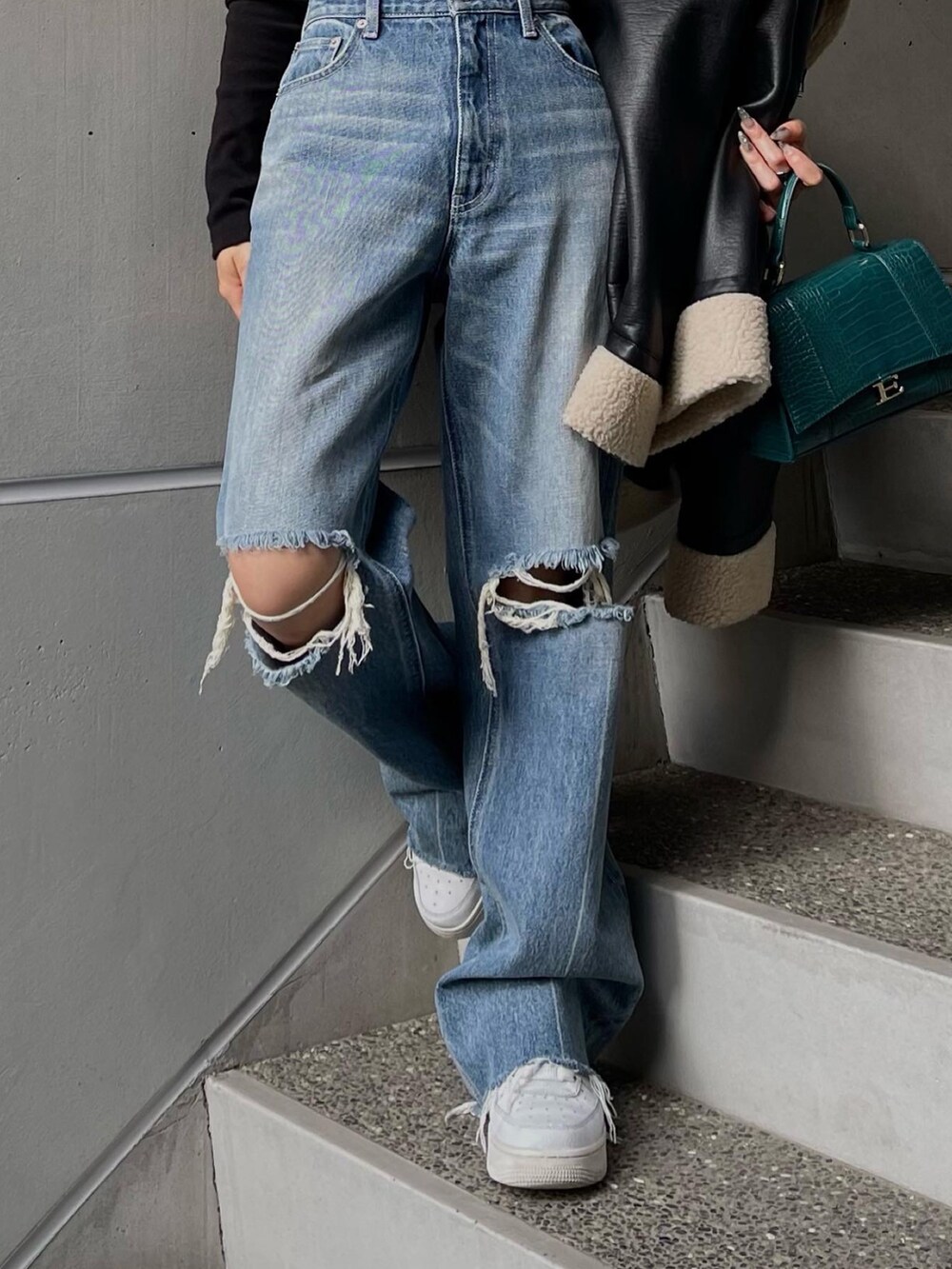 ブラック系のブルゾン、ブラック系のニット/セーター、ブルー系のデニムパンツを着用したレディースの秋コーディネートの5枚目の写真