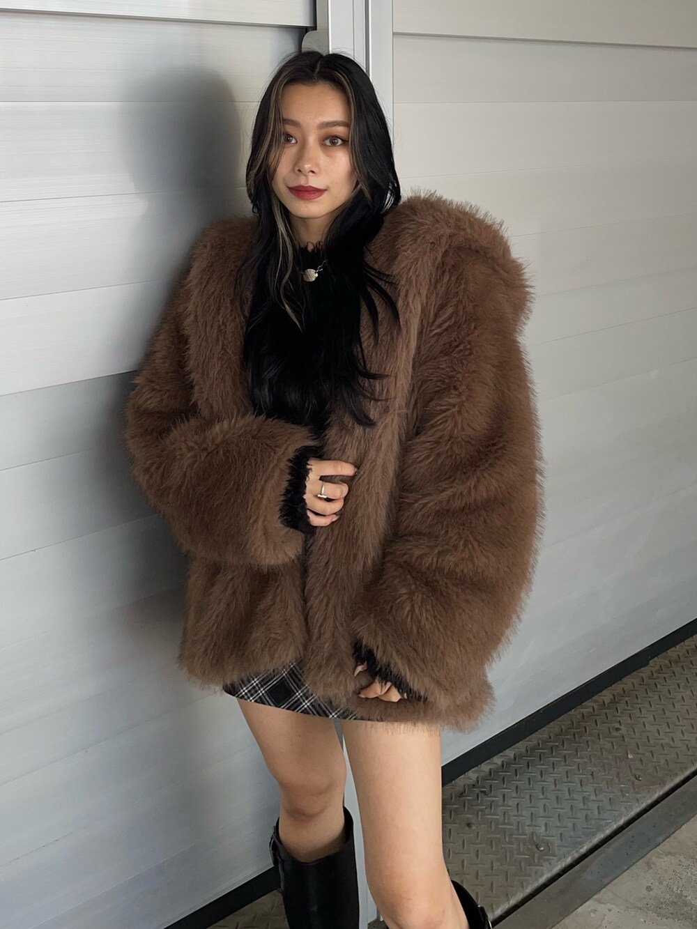 ブラウン系のブルゾン、ブラック系のニット/セーター、ブラック系のスカートを着用したレディースの秋コーディネートの2枚目の写真