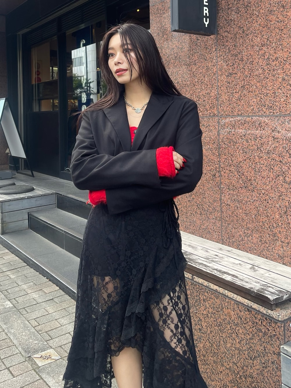 ブラック系のテーラードジャケット、レッド系のニット/セーター、ブラック系のスカートを着用したレディースの秋コーディネートの2枚目の写真