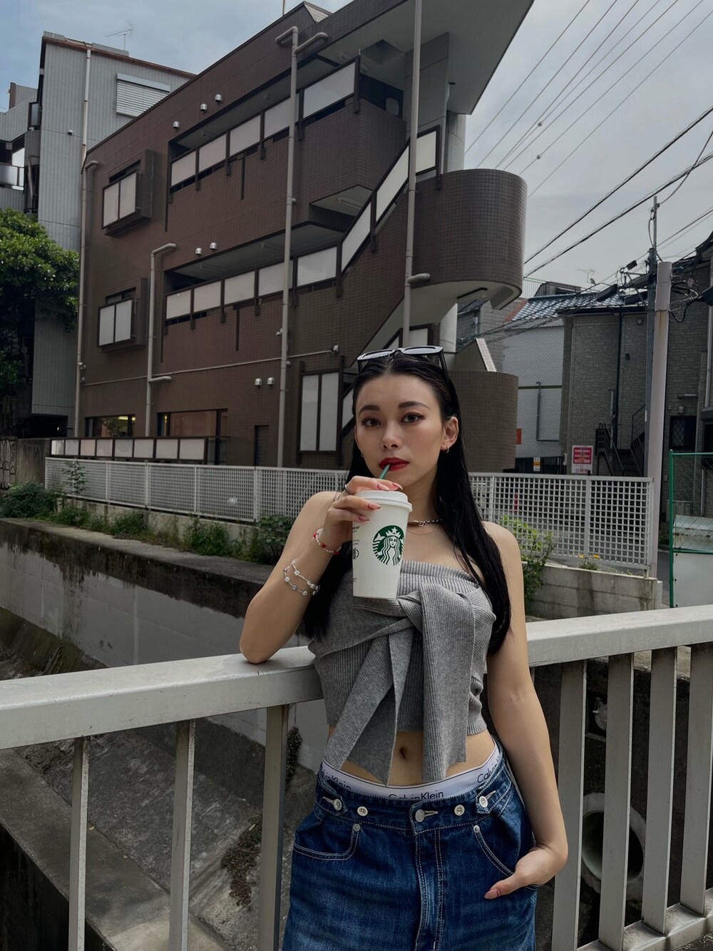 グレー系のチューブトップ、ブルー系のデニムパンツを着用したレディースの春コーディネートの4枚目の写真