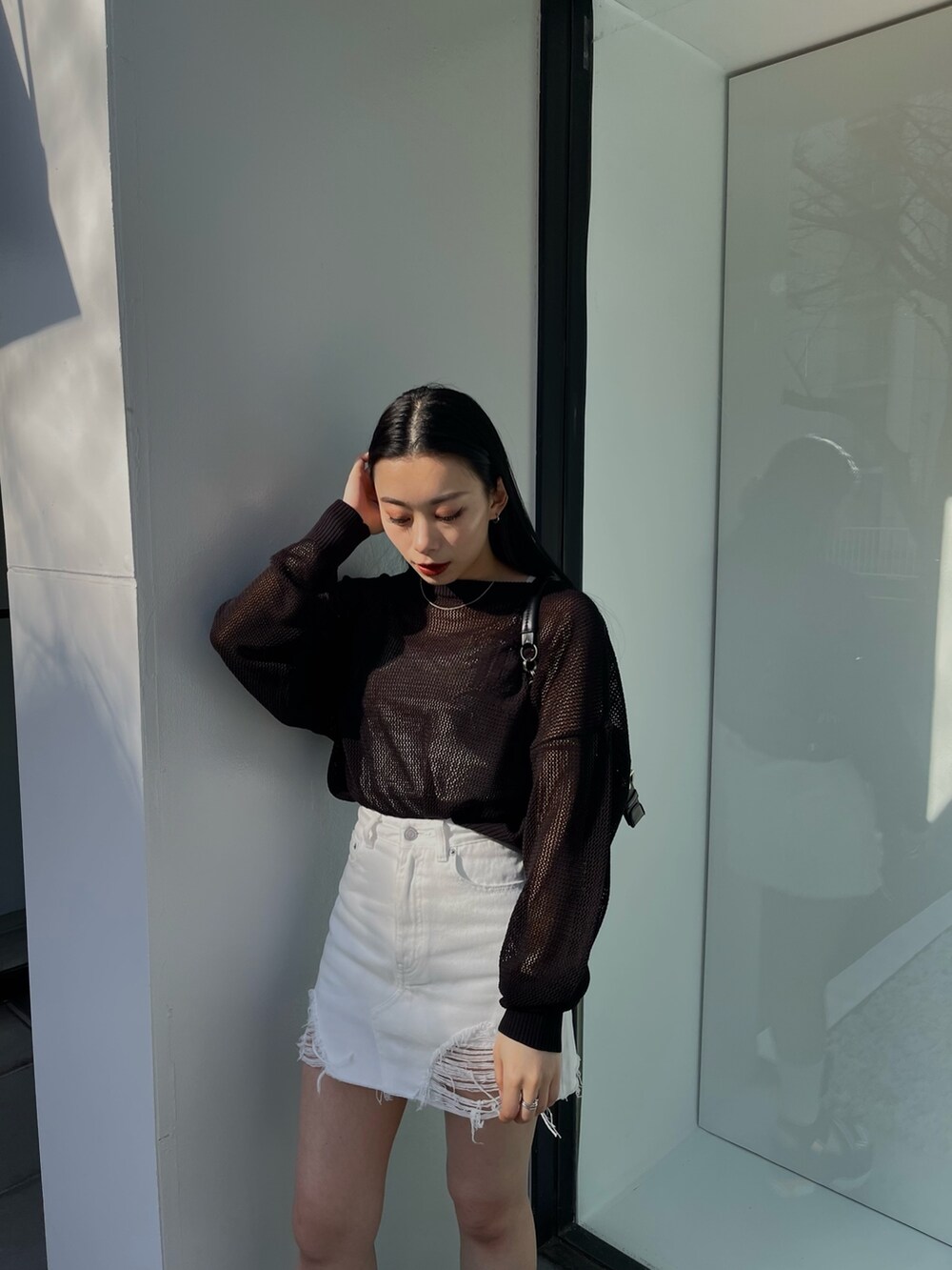 ホワイト系のデニムスカート、ブラック系のニット/セーター、ブラック系のサンダルを着用したレディースの春コーディネートの3枚目の写真