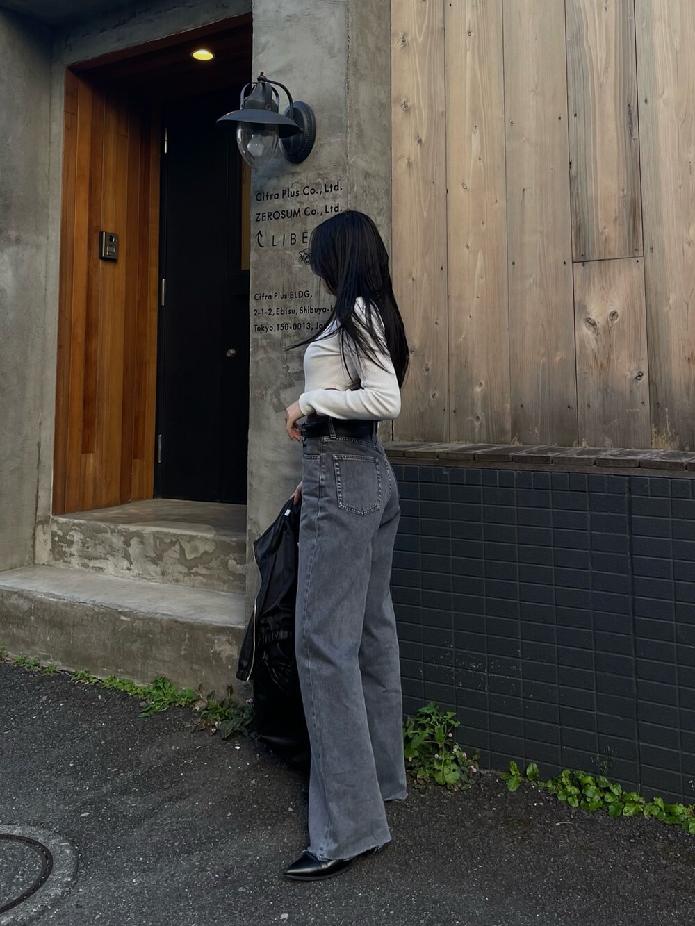 ホワイト系のTシャツ/カットソー、ブラック系のブルゾン、グレー系のデニムパンツを着用したレディースの冬コーディネートの2枚目の写真