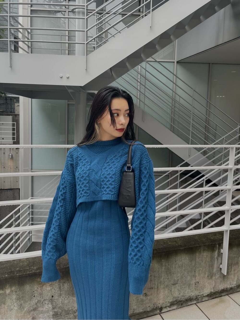 ブルー系のワンピース、ブラック系のハンドバッグ、ブラック系のブーツを着用したレディースの秋コーディネートの6枚目の写真