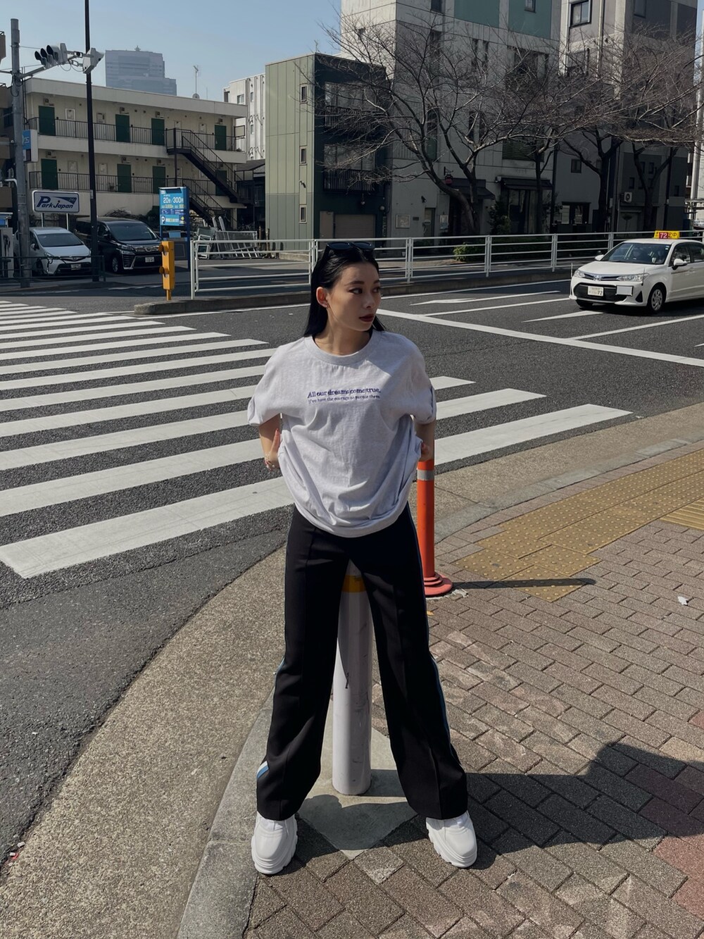 グレー系のTシャツ/カットソー、ブラック系のスラックス、ホワイト系のスニーカーを着用したレディースの春コーディネートの2枚目の写真