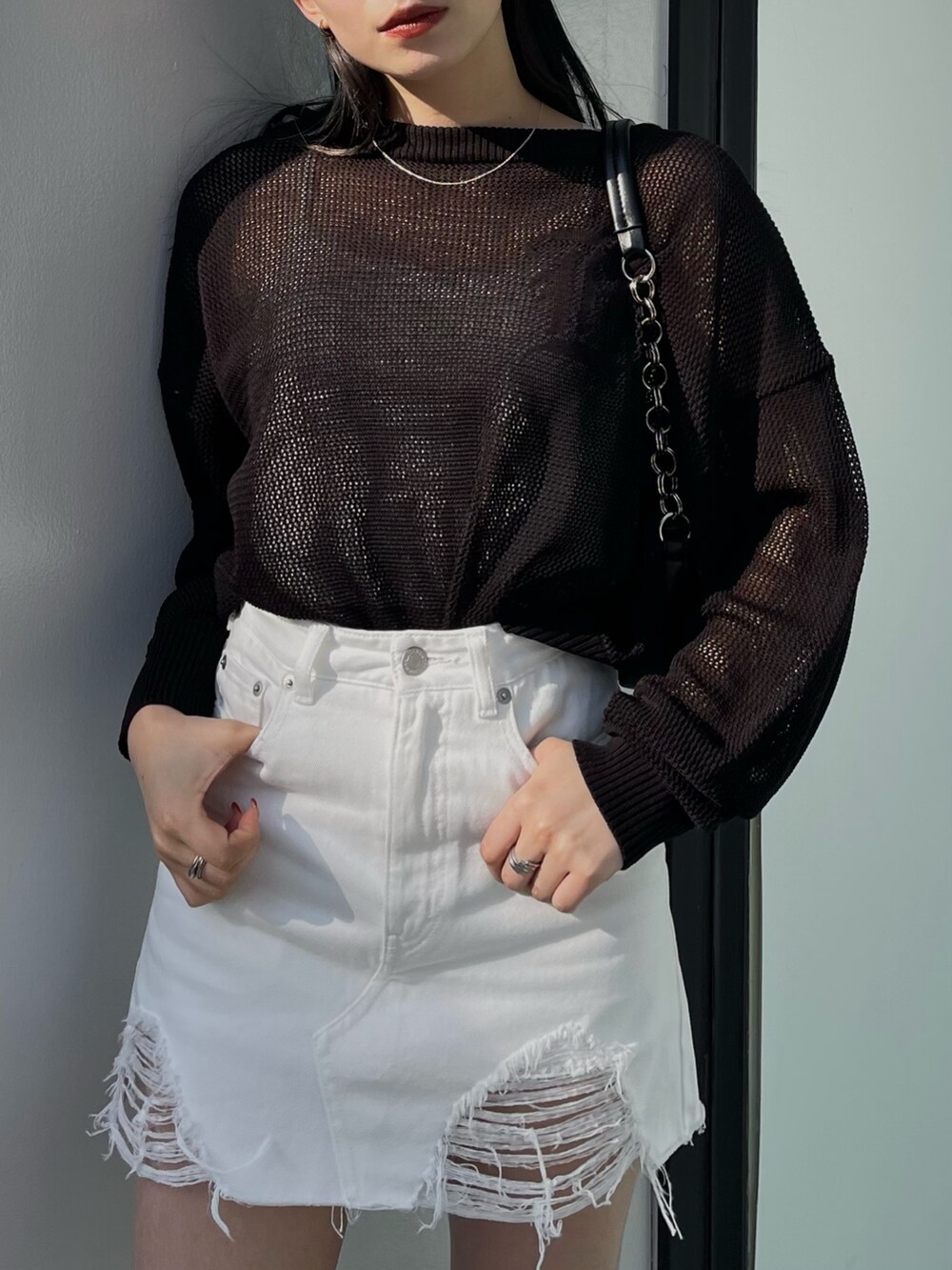 ホワイト系のデニムスカート、ブラック系のニット/セーター、ブラック系のサンダルを着用したレディースの春コーディネートの4枚目の写真