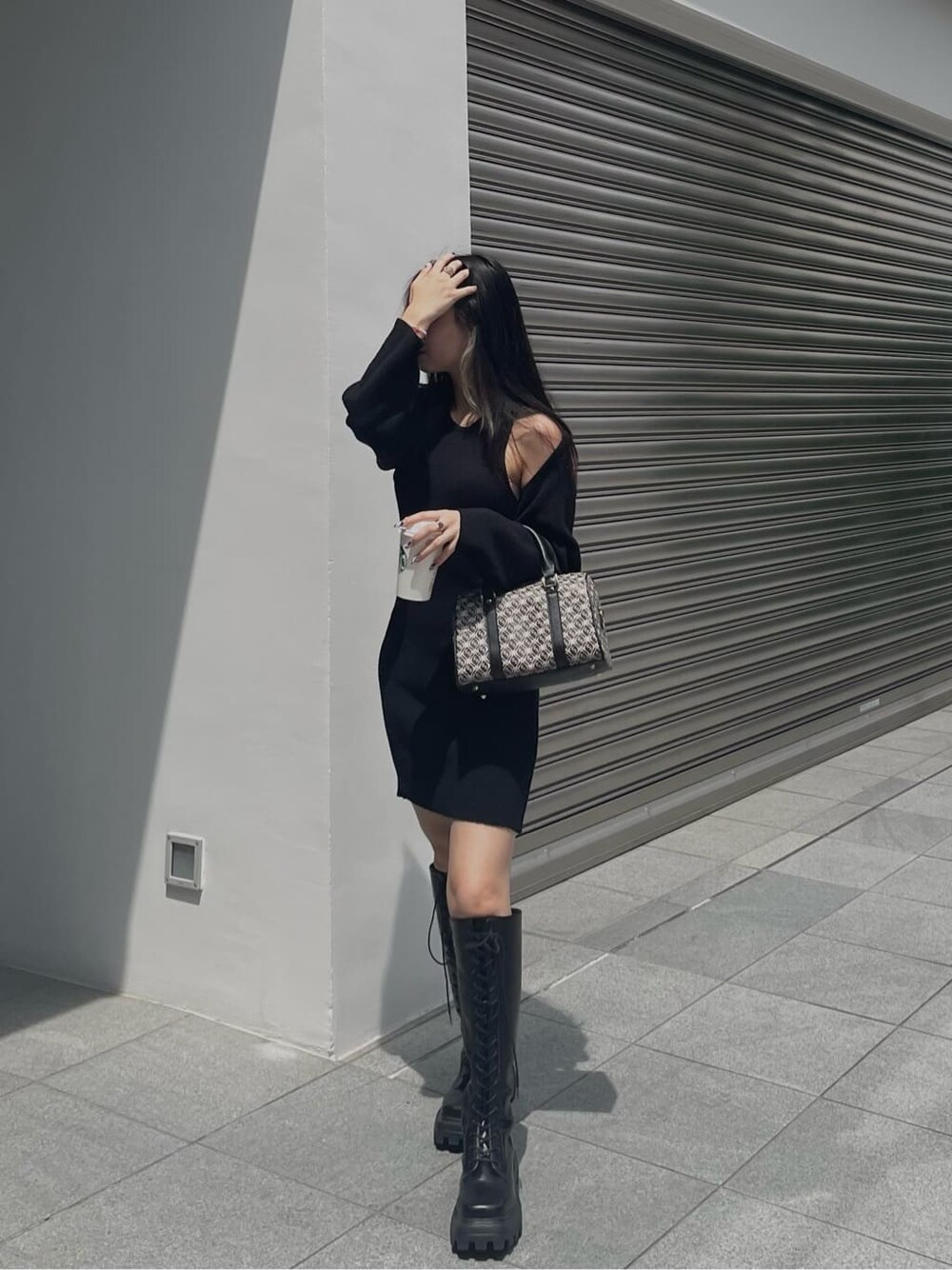 ブラック系のブーツ、ブラック系のワンピース、ブラック系のボストンバッグを着用したレディースの秋コーディネートの2枚目の写真