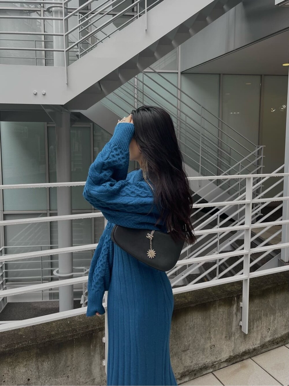 ブルー系のワンピース、ブラック系のハンドバッグ、ブラック系のブーツを着用したレディースの秋コーディネートの7枚目の写真