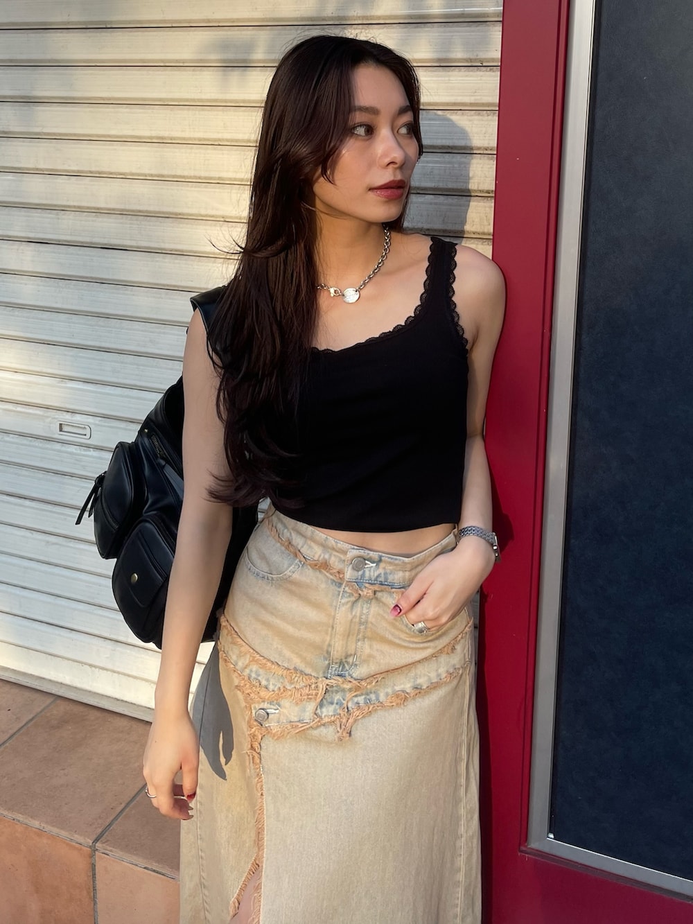 ブラック系のタンクトップ、ブルー系のデニムスカート、ブラック系のブーツを着用したレディースの夏コーディネートの3枚目の写真