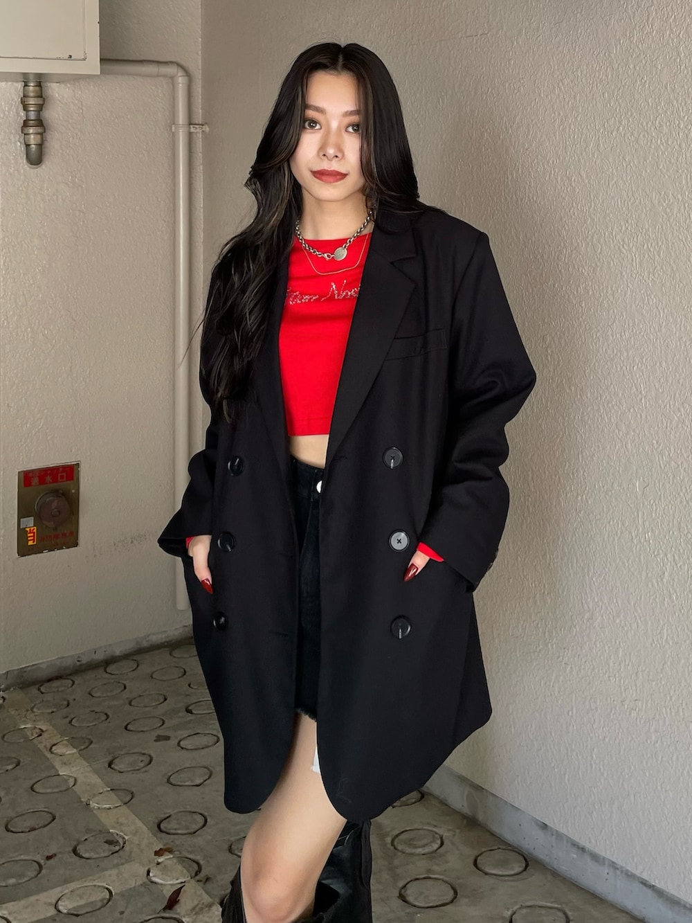 レッド系のTシャツ/カットソー、ブラック系のデニムスカート、ブラック系のブーツを着用したレディースの秋コーディネートの3枚目の写真