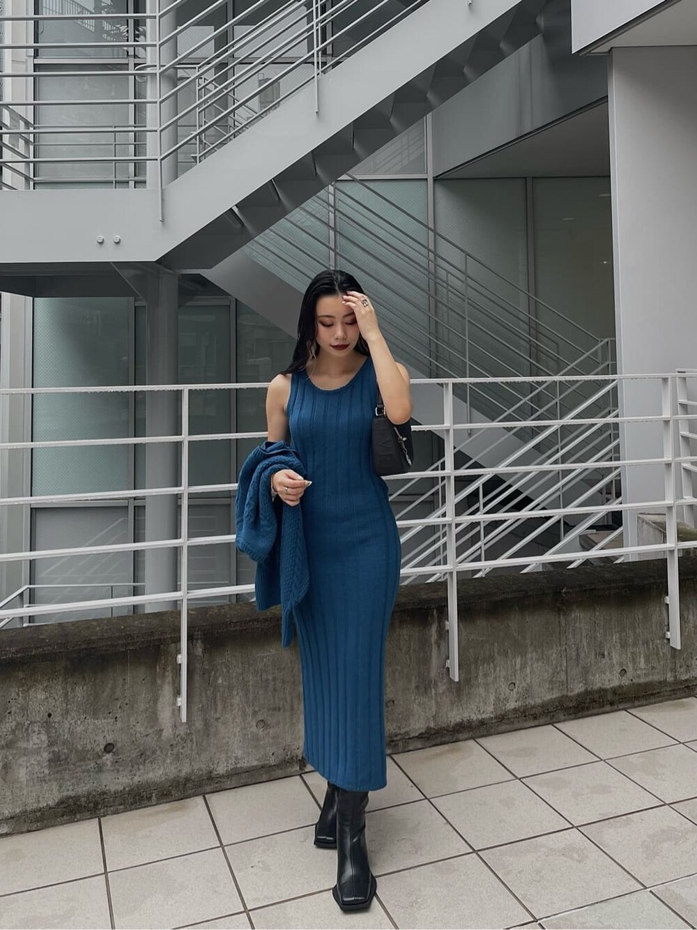 ブルー系のワンピース、ブラック系のハンドバッグ、ブラック系のブーツを着用したレディースの秋コーディネートの3枚目の写真