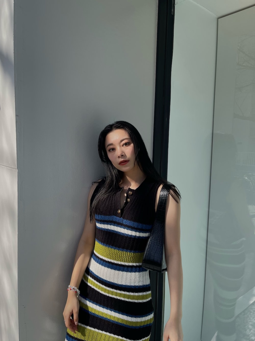 ブラック系のワンピース、ブラック系のハンドバッグを着用したレディースの春コーディネートの2枚目の写真