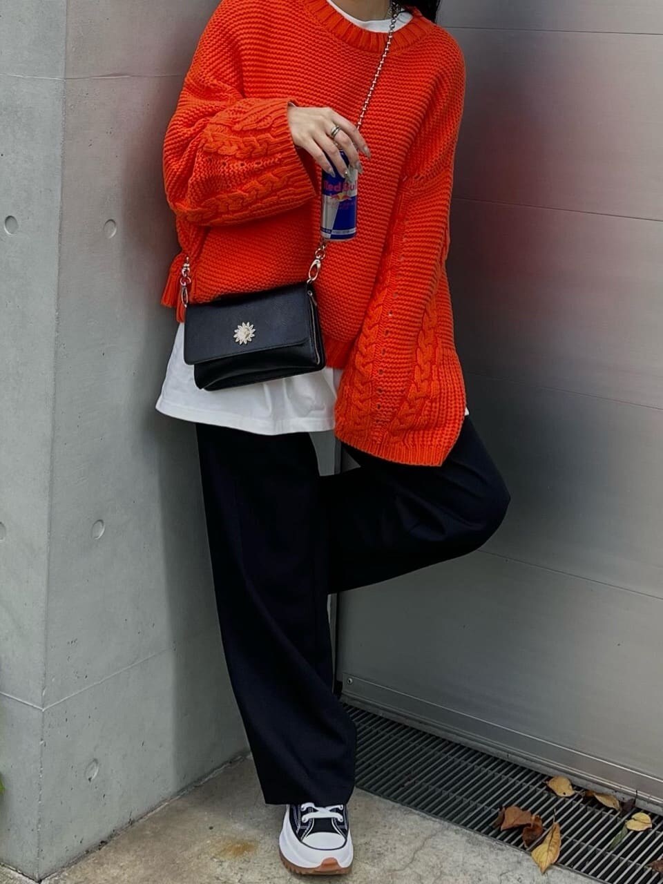 オレンジ系のニット/セーター、ブラック系のスラックスを着用したレディースの秋コーディネートの4枚目の写真