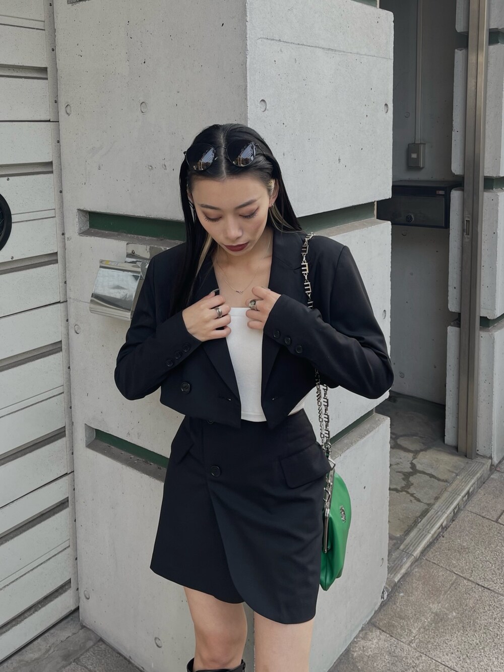 ブラック系のテーラードジャケット、ブラック系のスカート、グリーン系のショルダーバッグを着用したレディースの冬コーディネートの3枚目の写真