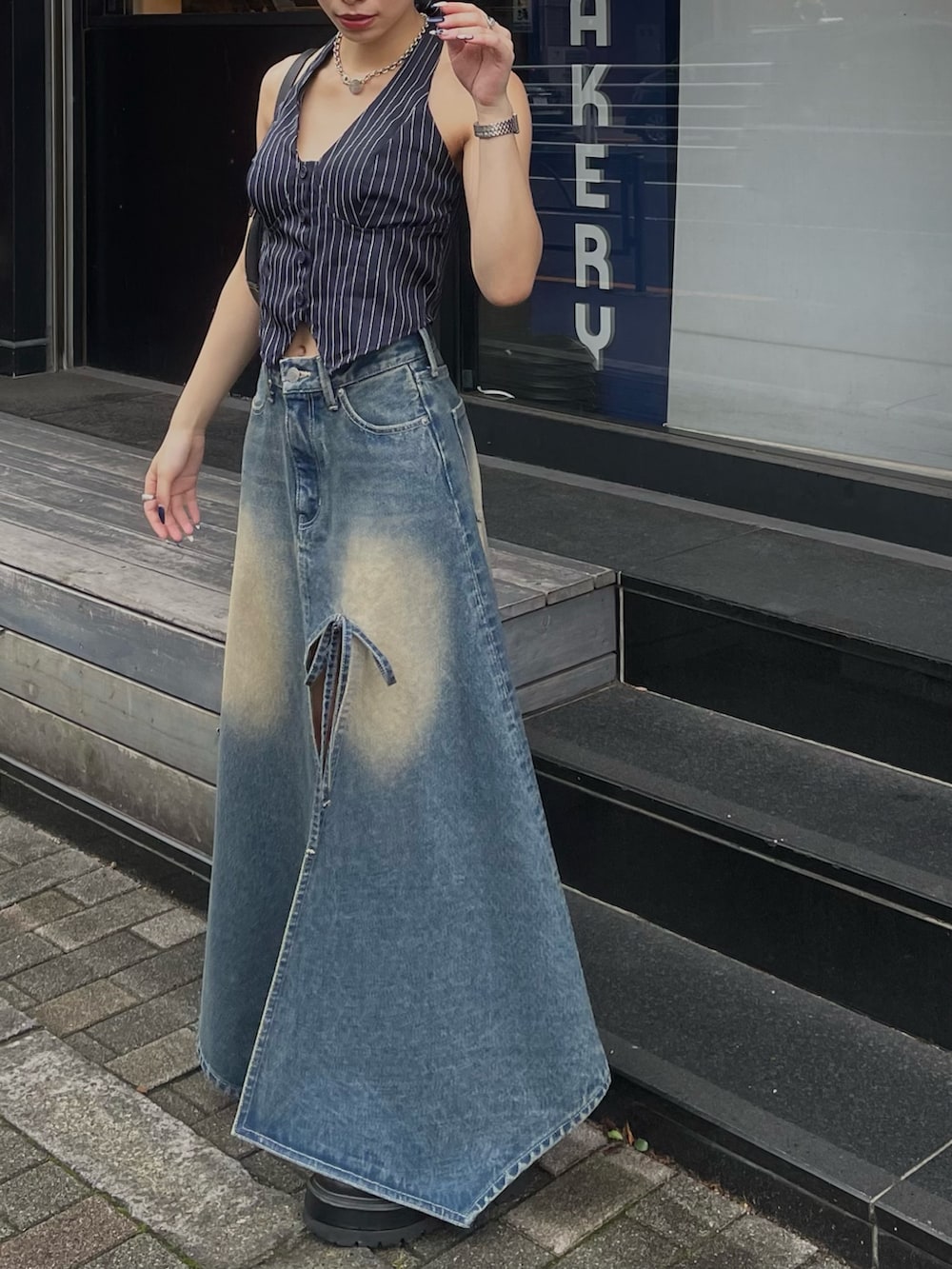 ブルー系のデニムスカート、ブラック系のブーツを着用したレディースの夏コーディネートの2枚目の写真