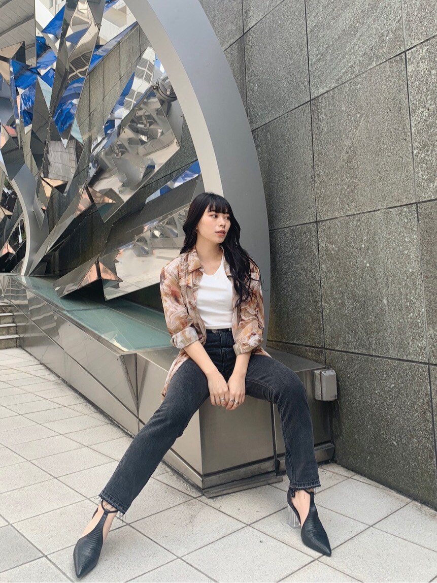 ブラック系のデニムパンツ、ブラック系のパンプス、ホワイト系のTシャツ/カットソーを着用したレディースの春コーディネートの2枚目の写真